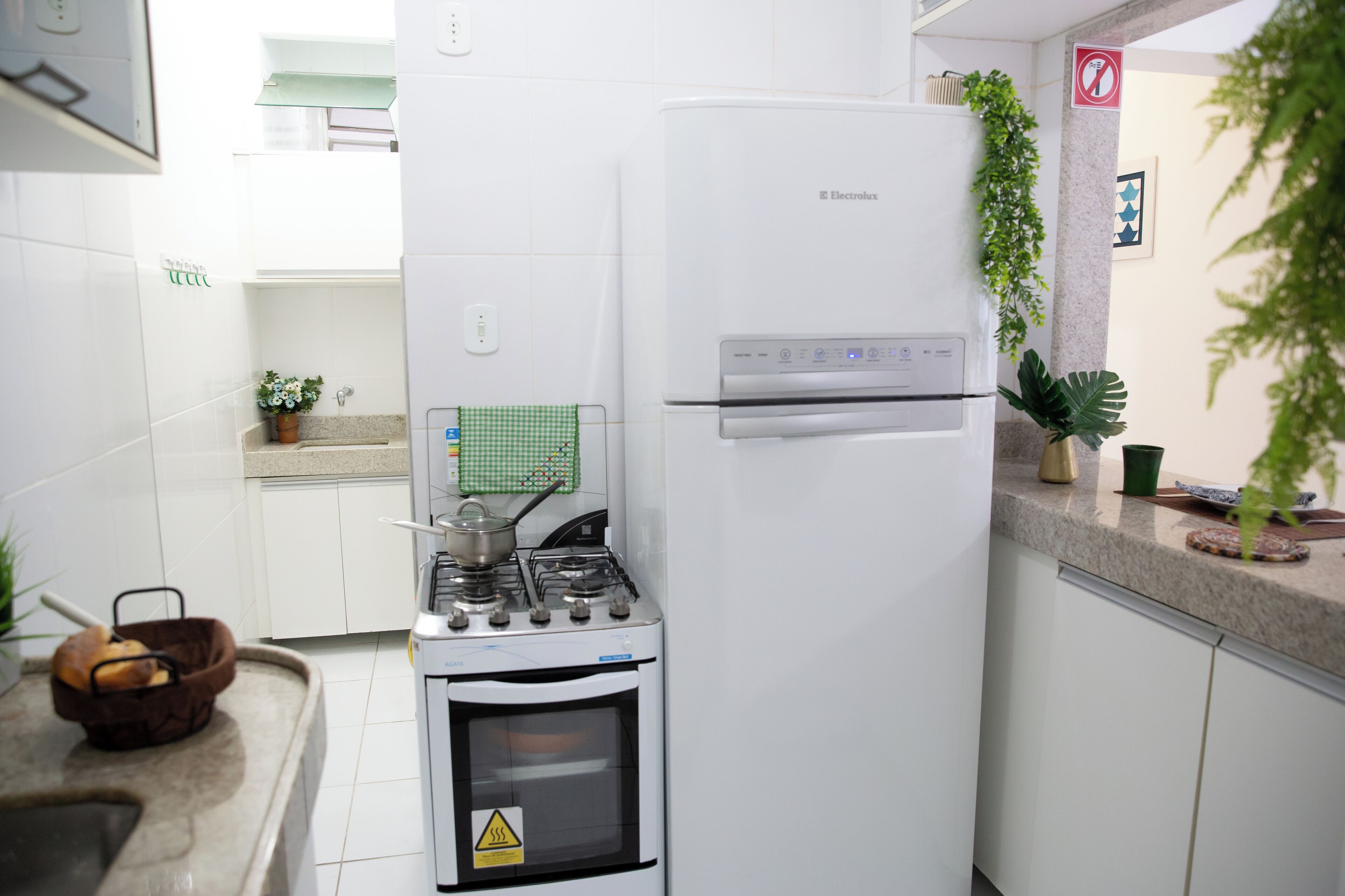 Uma cozinha compacta com fogão a gás, forno embutido e geladeira branca.