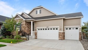 A two-story house with a stone facade, beige siding, and a double garage. - Pet Friendly New Luxury home on Buffalo Run Golf Course - Pool Table, BBQ (Commerce City)