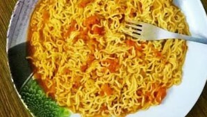 A plate of instant noodles with a fork on a wooden table. - Hotel Nutella Jaisalmer By GRB (Jaisalmer)