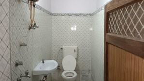 A small bathroom with a toilet, sink, and shower. - Hotel Nutella Jaisalmer By GRB (Jaisalmer)