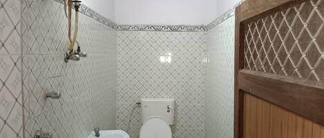 Un baño pequeño con inodoro, lavamanos y ducha.