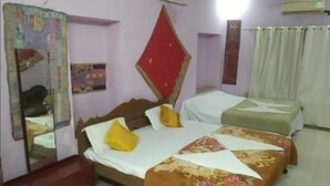 A bedroom with a bed, a bedside table, a mirror, and a wall-mounted air conditioner. - Hotel Nutella Jaisalmer By GRB (Jaisalmer)