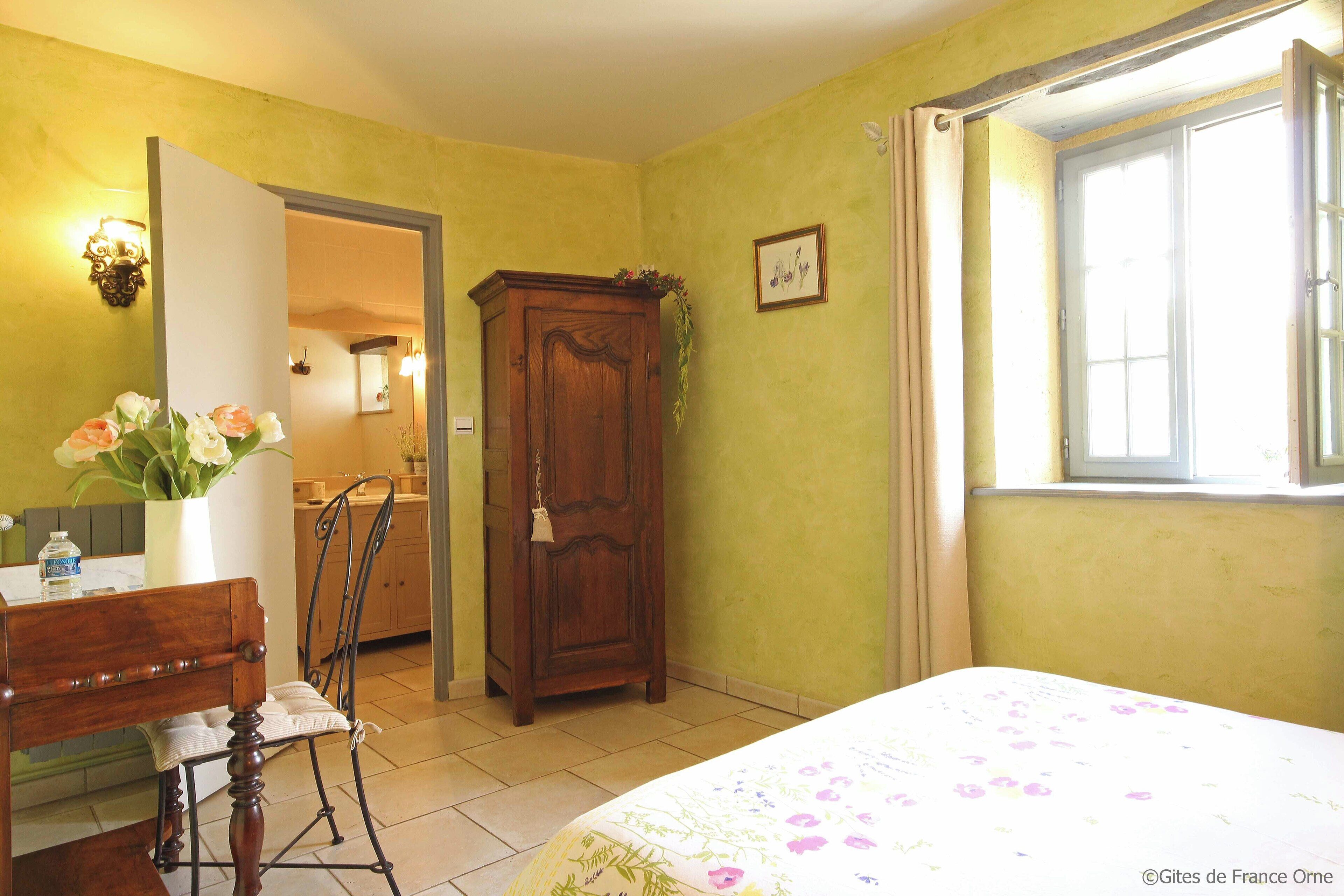 Une chambre à coucher avec un lit, une armoire en bois, une chaise, un bureau et une fenêtre.