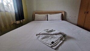 A neatly made bed with white linens and a folded towel on top. - Hotel O Widan Homestay (Samarinda)