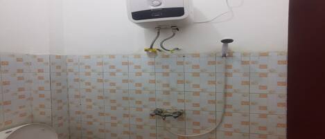 Un baño con inodoro, calentador de agua instalado en la pared y ducha.
