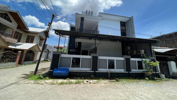 A modern two-story house with a balcony, a blue barrel, and a paved driveway. - Hotel O Widan Homestay (Samarinda)