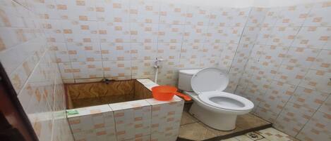 Une petite salle de bain avec des toilettes, une boîte en bois et un lavabo en plastique.