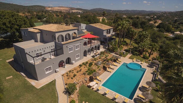 Une grande maison avec une piscine, un espace extérieur aménagé et une vue sur le paysage environnant.