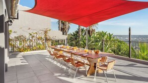Un espace de restauration en plein air avec une table et des chaises, un auvent rouge et une vue sur le paysage.