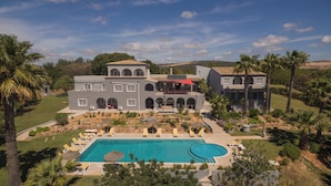 Un grand bâtiment à deux étages doté d’une piscine, d’un espace extérieur aménagé pour s’asseoir et d’un jardin paysager.