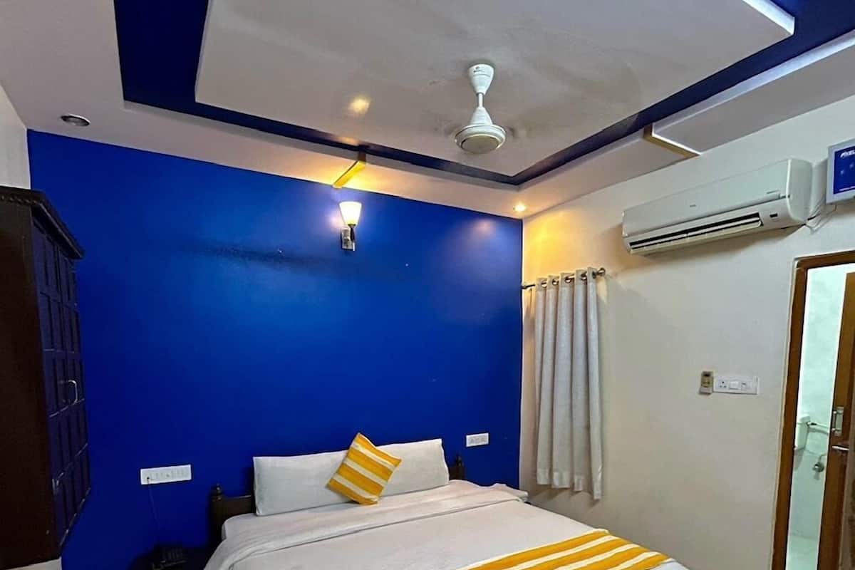 Een slaapkamer met een bed, een plafondventilator, een airconditioning en een nachtkastje.