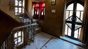A spacious interior with a marble staircase, a large arched window, and a decorative ceiling light.