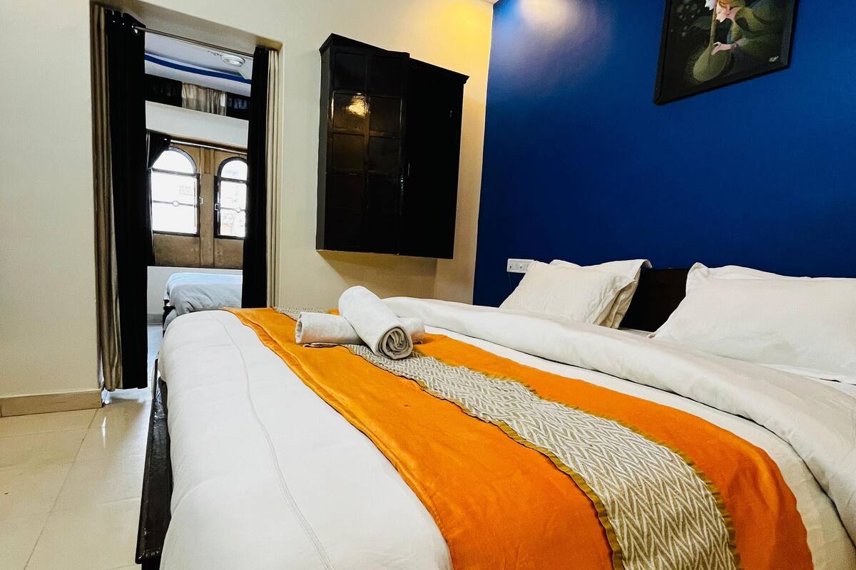 Een hotelkamer met een bed, een schilderij aan de muur en een raam met gordijnen.