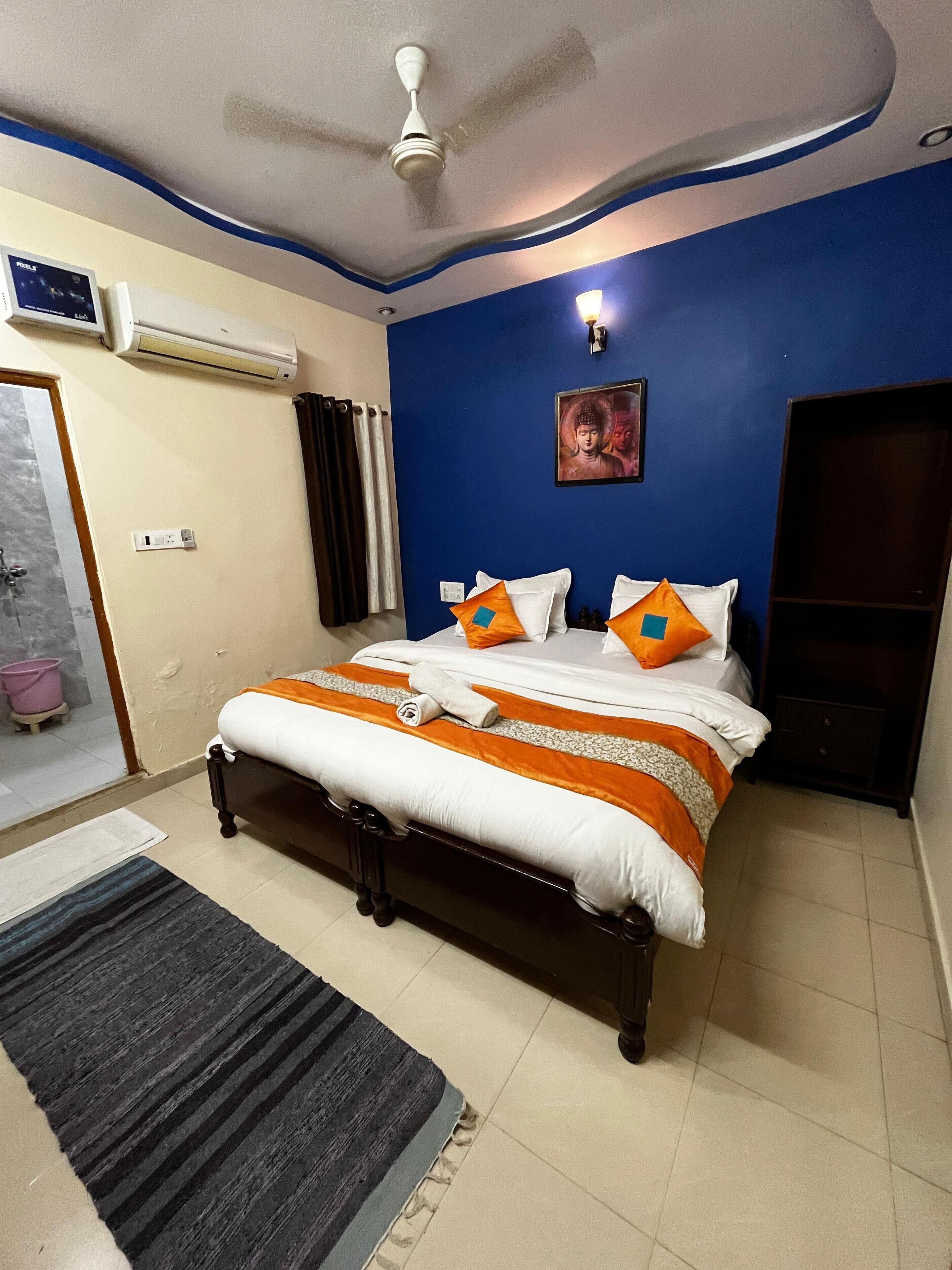 Un dormitorio con cama, ventilador de techo, aire acondicionado, lámpara de pared y ventana con cortinas.