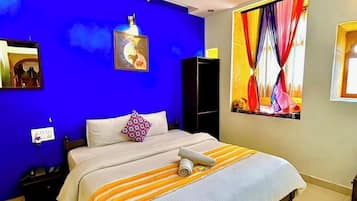 A bedroom with a bed, a ceiling fan, a painting, and a window with curtains.