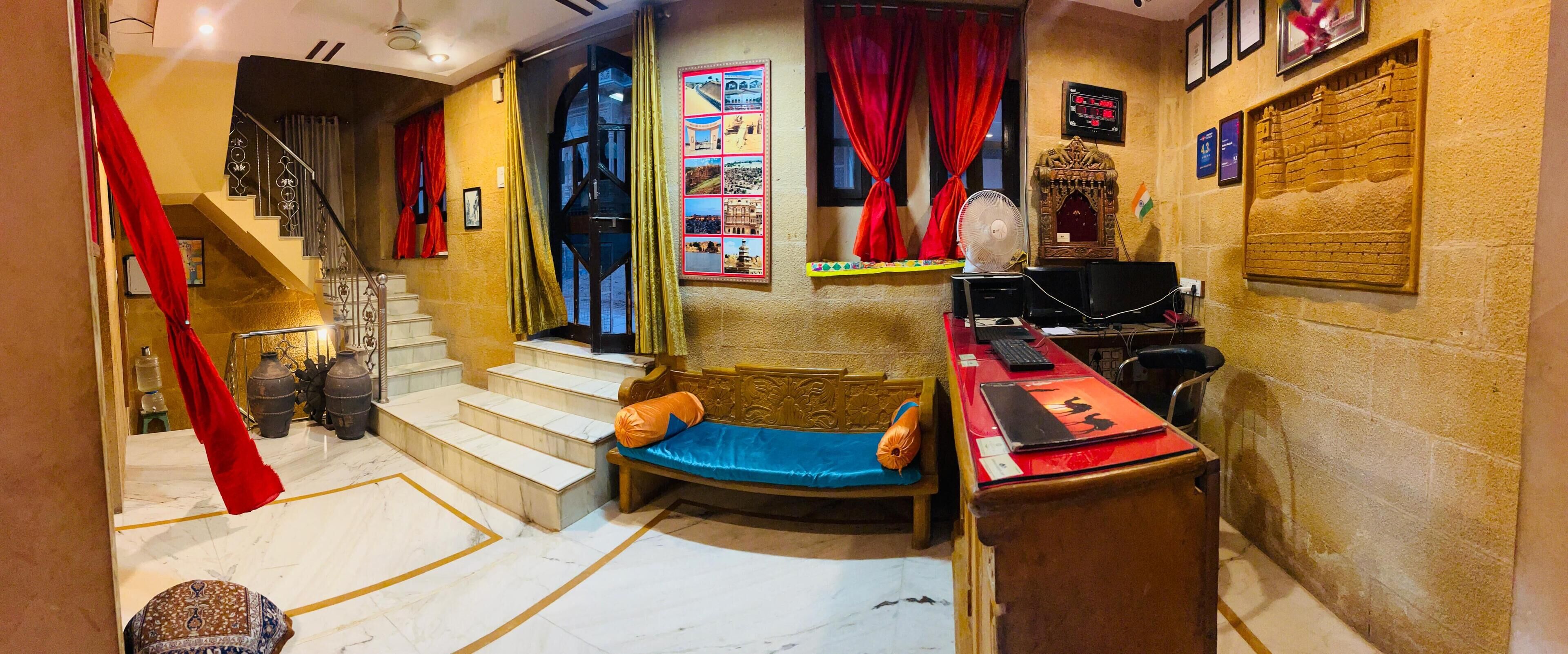 A room with a wooden bench, a desk with a computer, a fan, and a staircase.