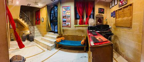A room with a wooden bench, a desk with a computer, a fan, and a staircase.