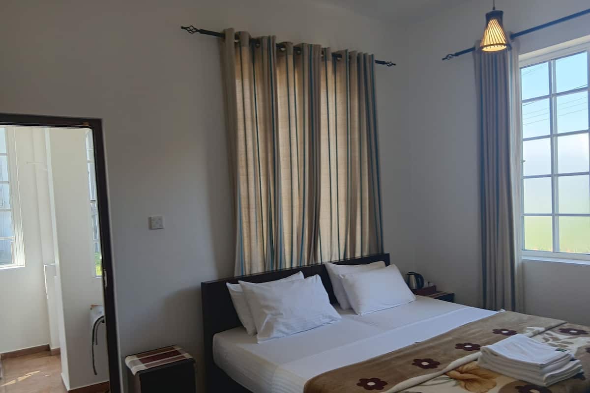 Ein Hotelzimmer mit Bett, Vorhängen, Fenster und Nachttisch.