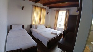 A hotel room with two single beds, a large bed, a desk, and a wardrobe.