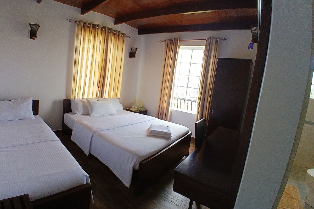 Ein Hotelzimmer mit zwei Einzelbetten, einem großen Bett, einem Schreibtisch und einem Kleiderschrank.