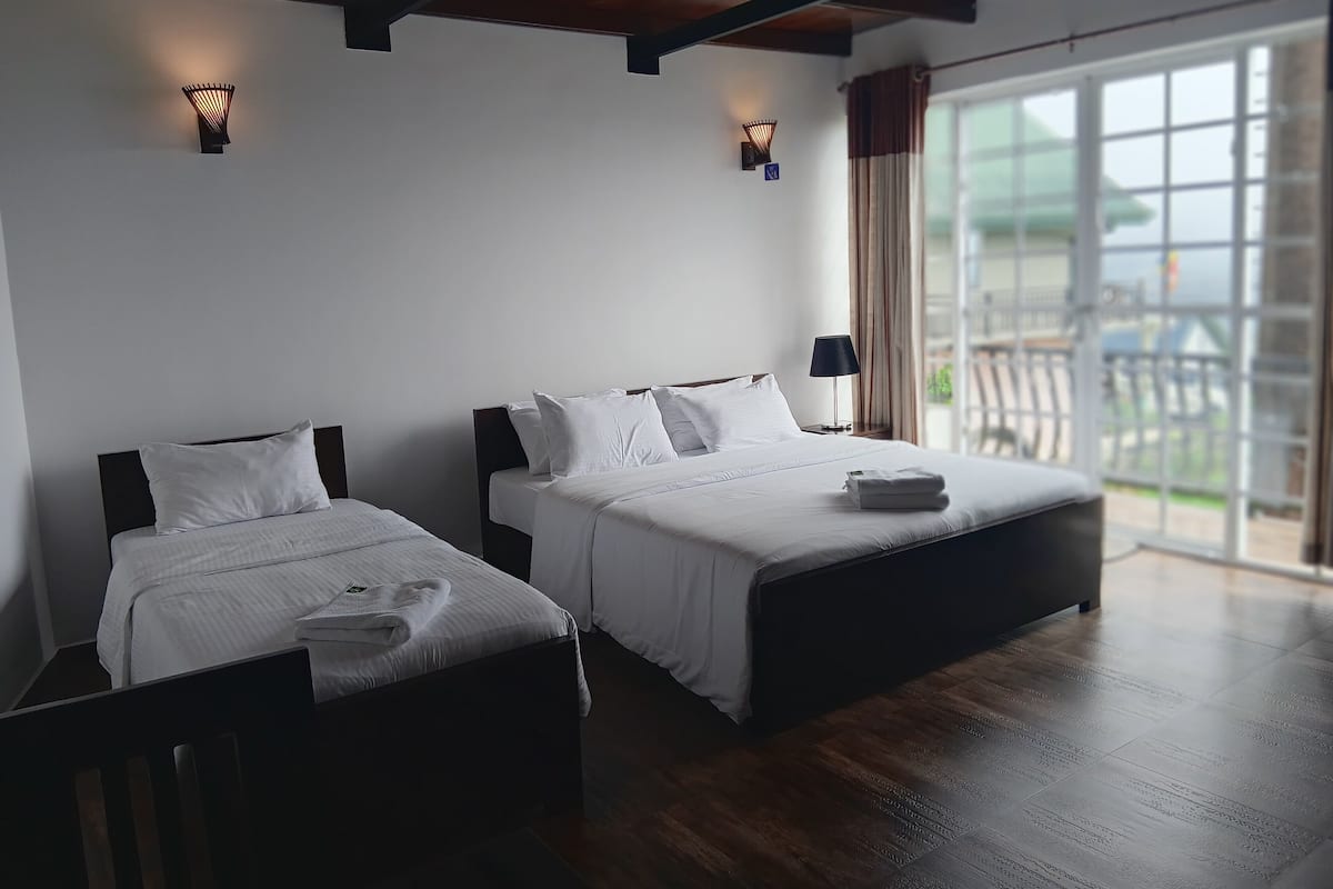 Ein Hotelzimmer mit zwei Betten, einem großen Fenster mit Aussicht und einer Decke mit sichtbaren Balken.