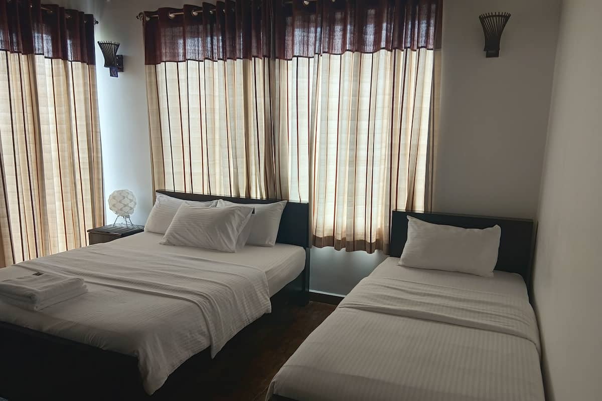 Ein Hotelzimmer mit zwei Betten, jeweils mit weißen Leinen und Kissen, einem dunklen Kopfteil und einer Wandlampe.