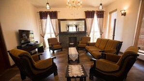 A living room with a fireplace, two armchairs, a sofa, a coffee table, and a television.