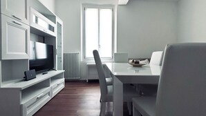 A modern kitchen with white cabinetry, a built-in oven, and a dining area with a white table and chairs. - Farini House - apartment in Modena (Modena)