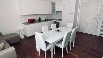 Una cocina moderna con armarios blancos, una mesa de comedor con sillas y un horno empotrado.
