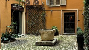 A courtyard with a cobblestone floor, a stone planter, and a building with a sign reading "Galleria Antica Aquaria". - Farini House - apartment in Modena (Modena)