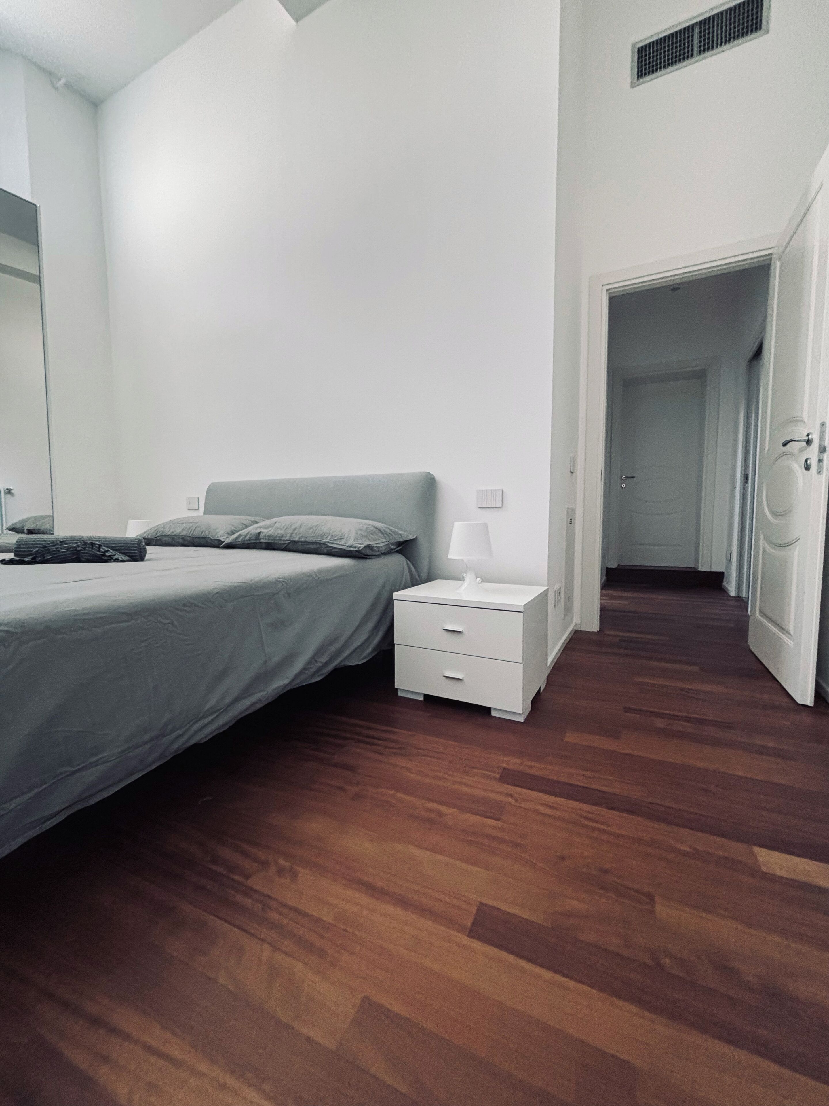 A bedroom with a bed, bedside table, and a nightstand.