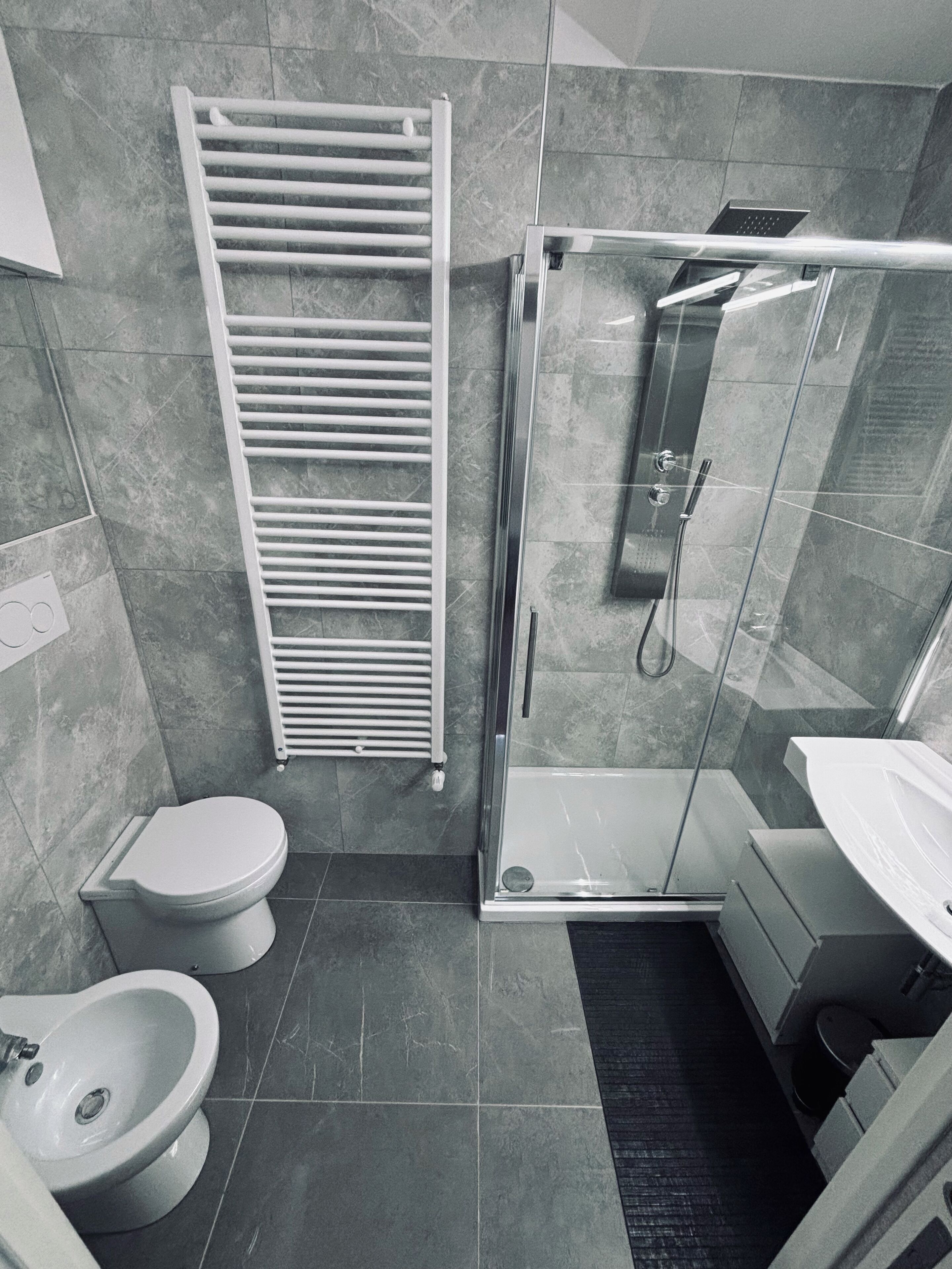 A modern bathroom with a glass-enclosed shower, a white toilet, and a bidet.