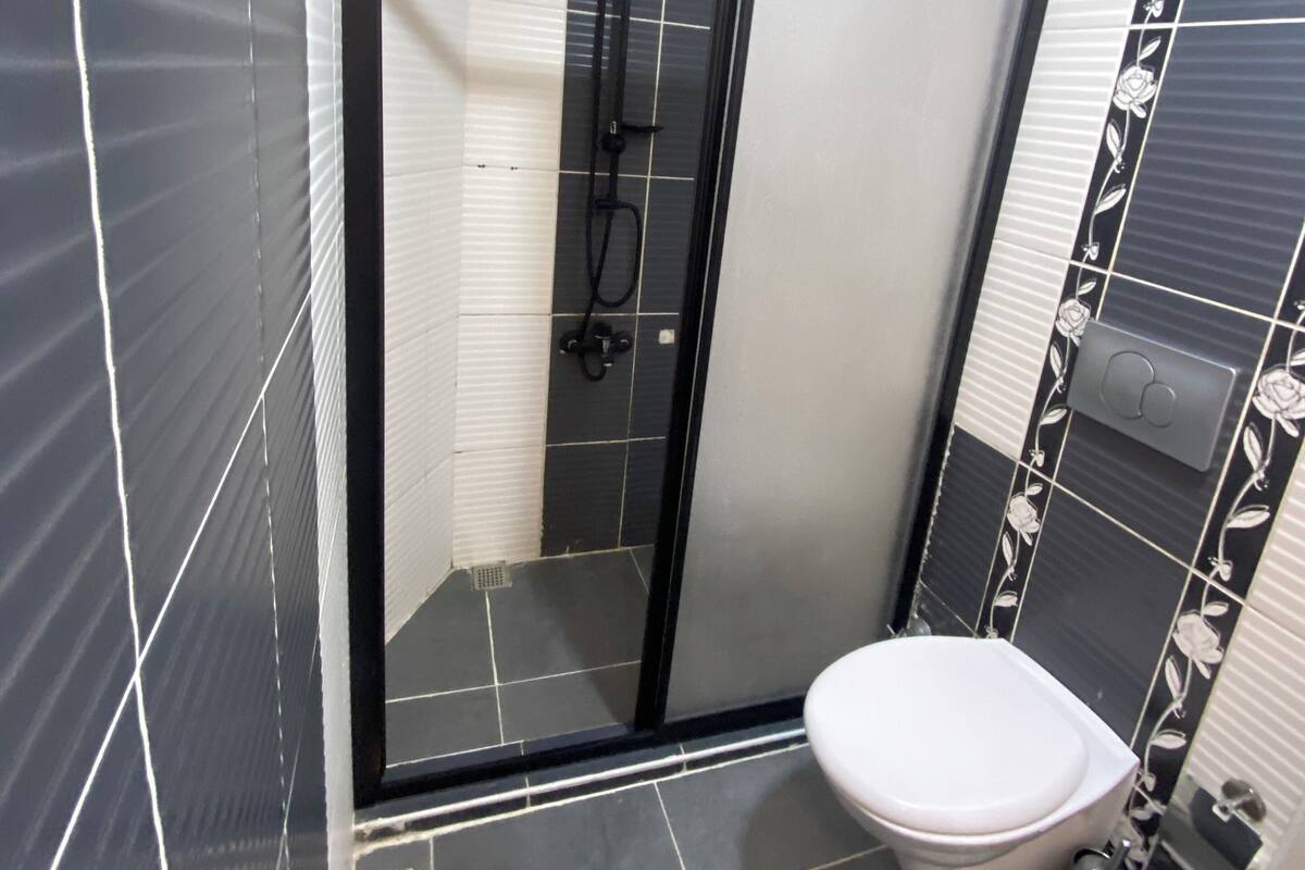 A bathroom with a glass-enclosed shower, a toilet, and a sink.