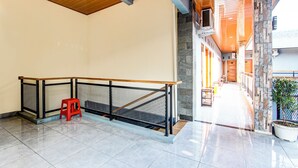A spacious indoor area with a tiled floor, a wooden ceiling, a metal railing, and a red stool.