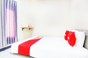 A hotel room with a bed, a bedside table, a lamp, and a curtain.