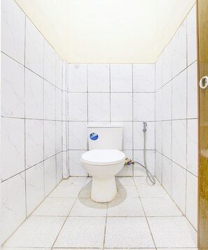 A small, tiled bathroom with a toilet and a shower.
