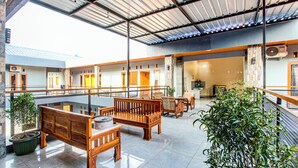 A spacious indoor area with wooden benches, potted plants, and a high ceiling with metal beams.