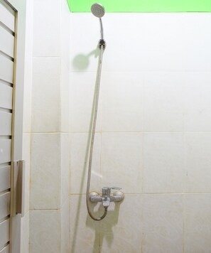 Une douche équipée d’un pommeau de douche à main et d’un robinet mural.