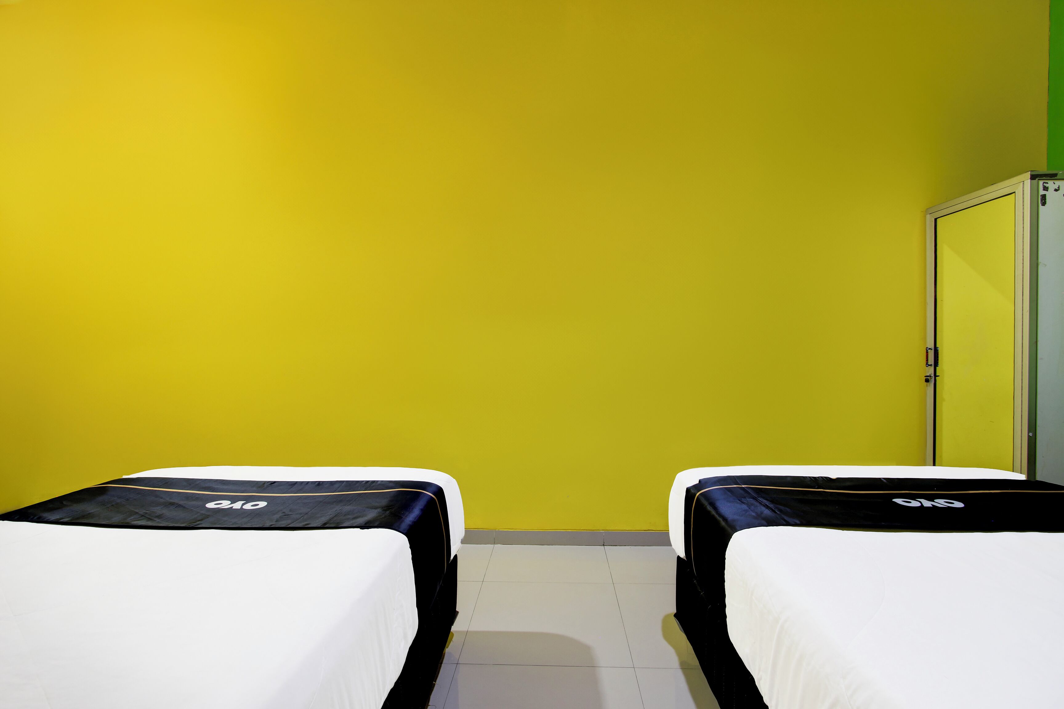 A room with two beds, a green wall, and a white door.