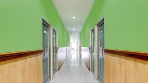 A hallway with green walls and wooden paneling, leading to a bright room with a large window. - Hotel O Jalan Slamet Riyadi Near Bandara Adi Soemarmo Formerly Amanah Sejahtera (Ngemplak)