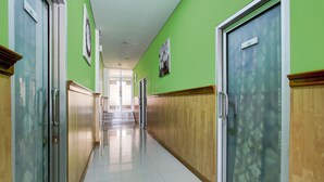 A hallway with green walls, wooden paneling, and a tiled floor. - Hotel O Jalan Slamet Riyadi Near Bandara Adi Soemarmo Formerly Amanah Sejahtera (Ngemplak)
