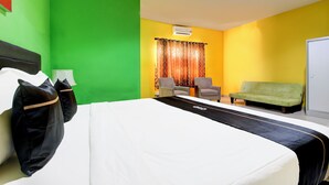 A hotel room with a large bed, two armchairs, a sofa, and a green wall. - Hotel O Jalan Slamet Riyadi Near Bandara Adi Soemarmo Formerly Amanah Sejahtera (Ngemplak)
