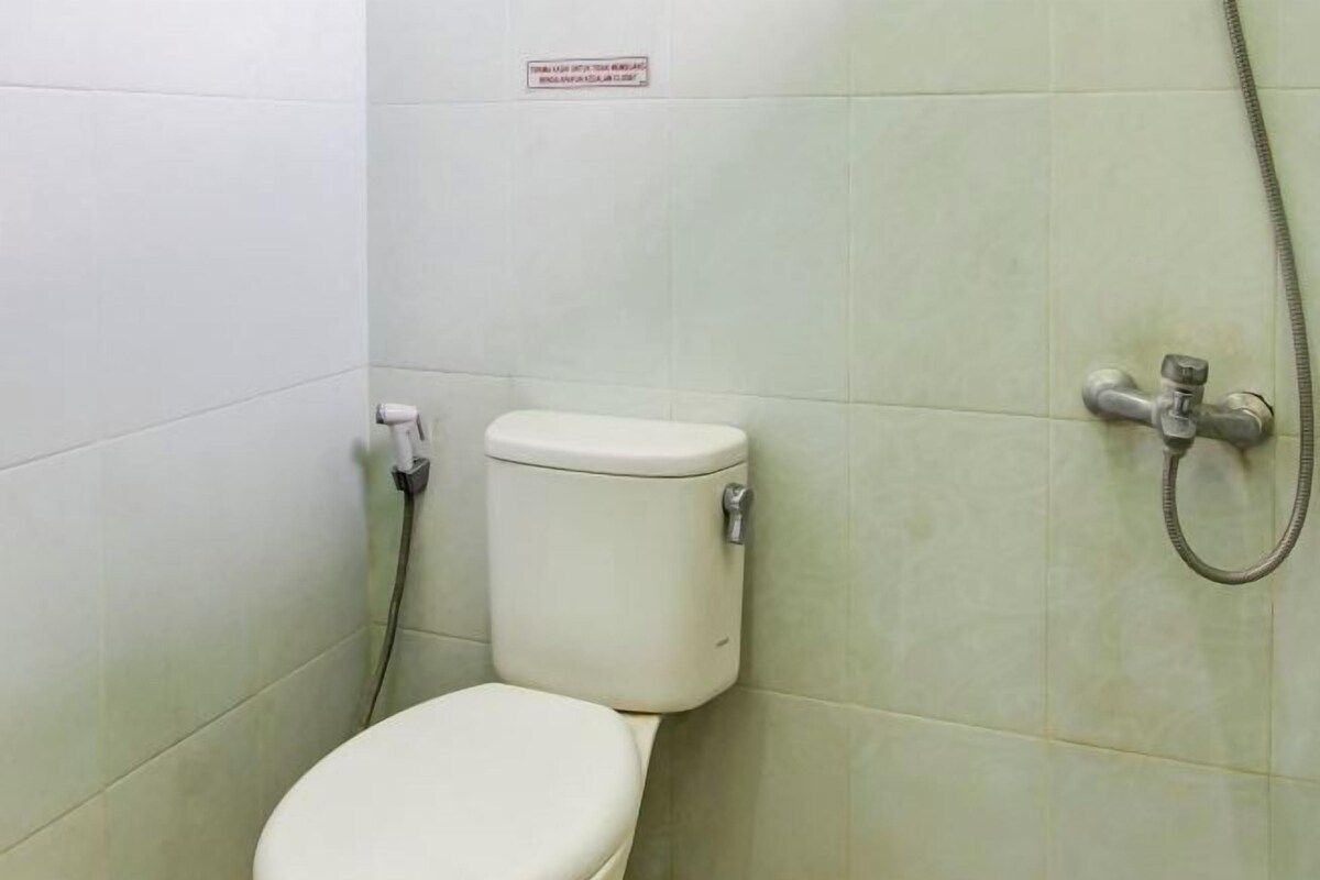 Een kleine, privé badkamer met toilet, douche en een bordje aan de muur.