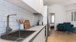 Egy modern konyha rozsdamentes acél mosogatóval, fehér szekrényekkel és egy fa vágódeszkával.