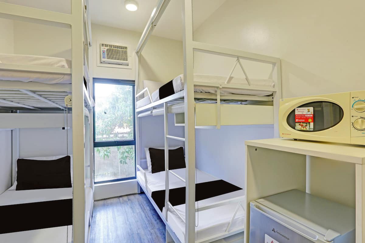 A bunk bed room with a microwave and a small refrigerator.