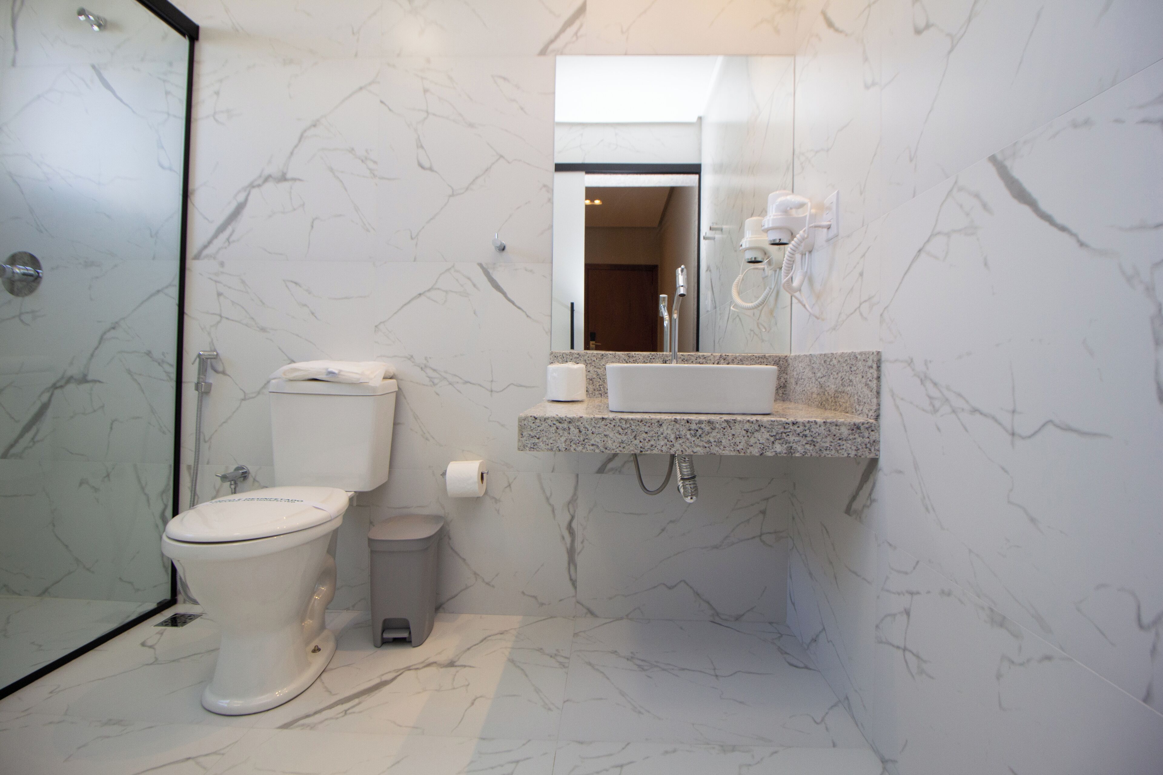 Ein modernes Badezimmer mit Toilette, Waschbecken und Spiegel.