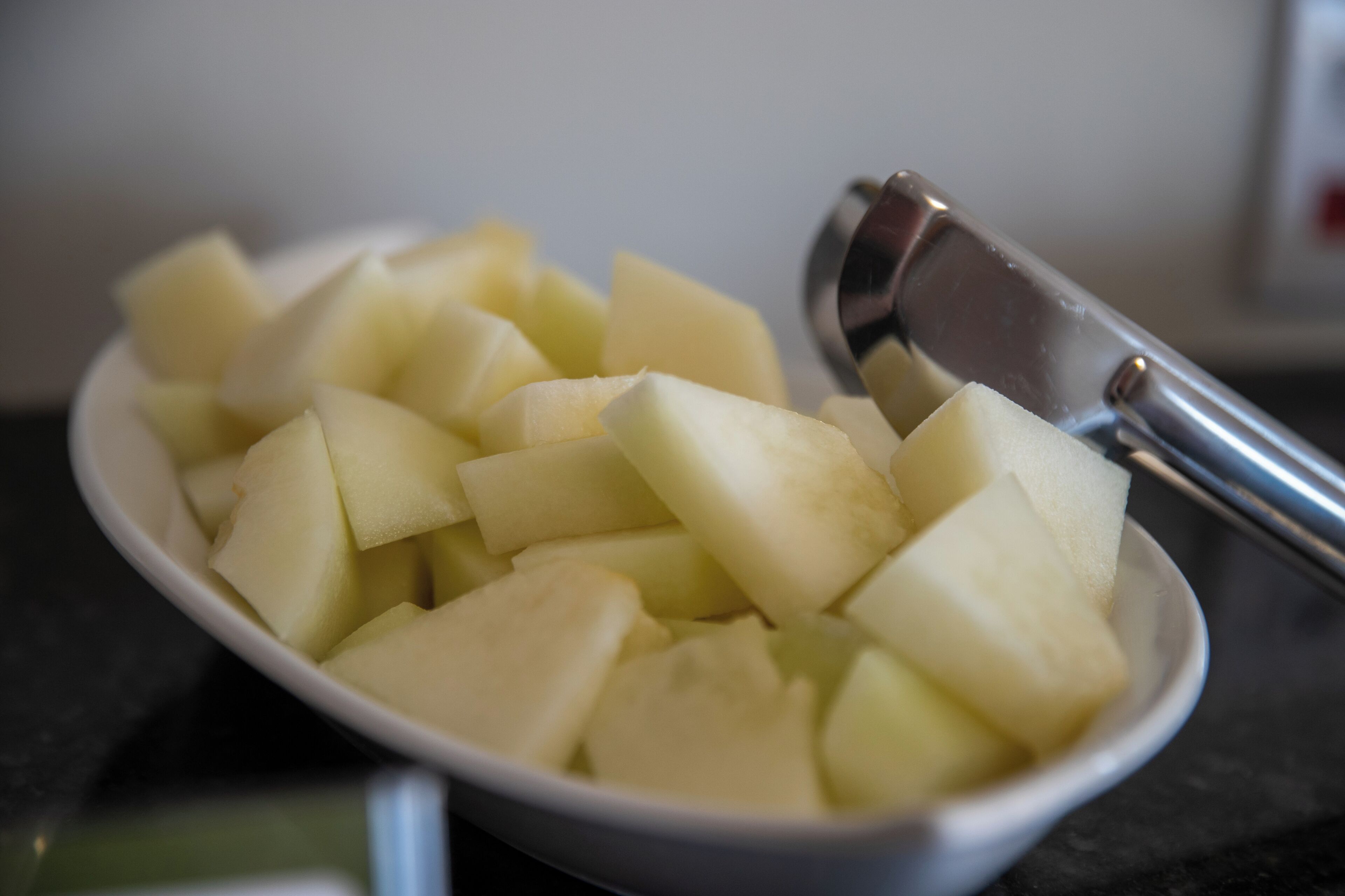 Un tazón de papas cortadas en cubos con un utensilio de metal.