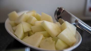 Un tazón de papas cortadas en cubos con un utensilio de metal.
