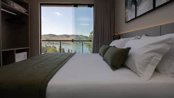 A hotel room with a bed, a view of a lake, and a balcony.