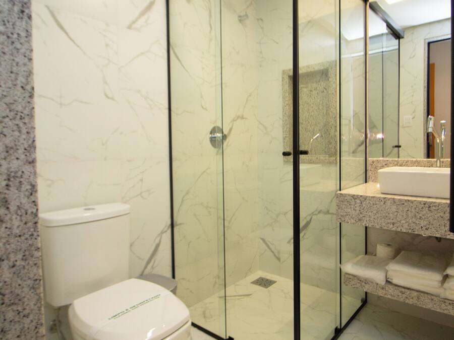 A modern bathroom with a glass-enclosed shower, a white toilet, and a marble floor.